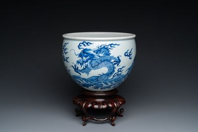 A Chinese blue and white 'dragons and carps' jardinière on wooden stand, 19/20th C.