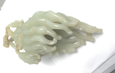 A jade buddha hand on a carved wood stand, Qing dynasty, 18th C.