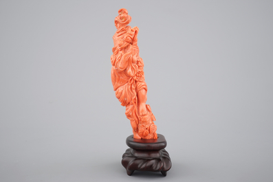 A Chinese carved red coral figure on a wooden stand, 19/20th C.