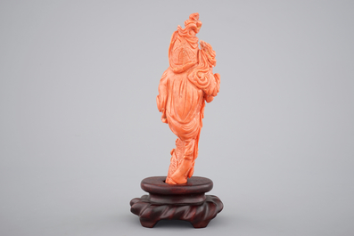 A Chinese carved red coral figure on a wooden stand, 19/20th C.