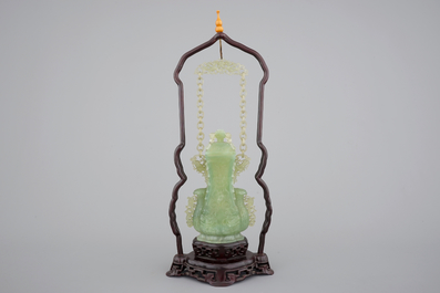 A Chinese carved green jadeite vase and cover on elaborate wooden stand, 19/20th C.