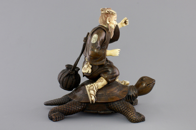 A signed Japanese carved ivory and wood figure of an immortal seated on a turtle, 19th C.