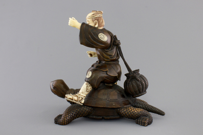 A signed Japanese carved ivory and wood figure of an immortal seated on a turtle, 19th C.