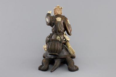 A signed Japanese carved ivory and wood figure of an immortal seated on a turtle, 19th C.