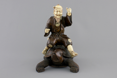 A signed Japanese carved ivory and wood figure of an immortal seated on a turtle, 19th C.