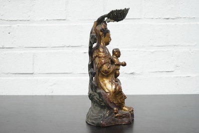 A Chinese bronze and gilt Buddha with child, seated beneath a bodhi tree, 17/18th C.