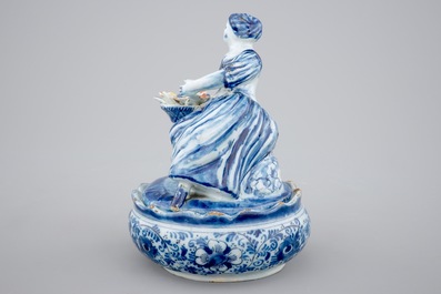 A polychrome Dutch Delft butter tub with a seated lady, 18th C.