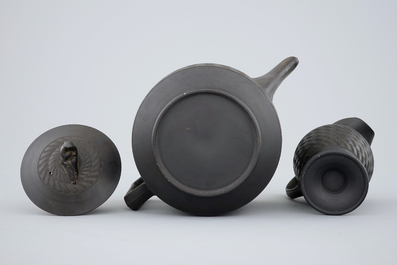 A Wedgwood black basalt teapot and cream jug, 19th C.