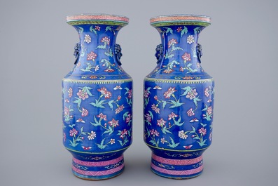 A pair of Chinese blue ground famille rose vases with flowers, 19th C.