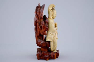 A fine figure of a Guanyin in soapstone on a wooden base, 18/19th C.