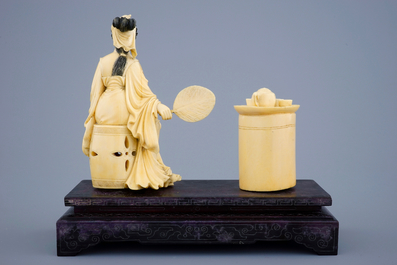 A Chinese carved ivory group of a lady near a tea table on a wood base, 19th C.