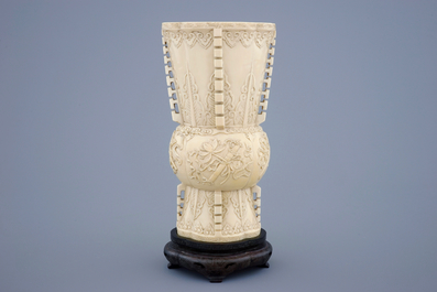 Een Chinese ivoren vaas naar archa&iuml;sch voorbeeld op een houten sokkel, 19e eeuw
