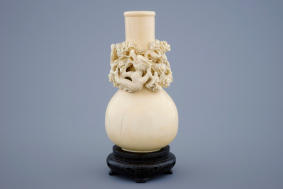 A Chinese carved ivory dragon vase on a wooden base, early 20th C.