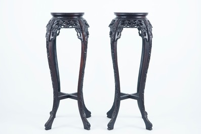 A pair of tall round Chinese carved wood stands with marble top, 19/20th C.