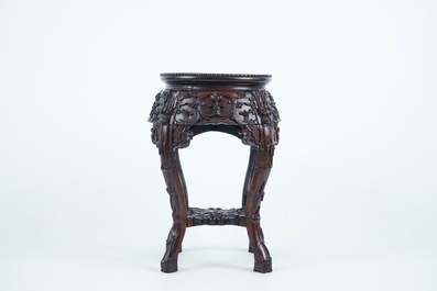 A carved round Chinese wood stand with marble top, 19/20th C.