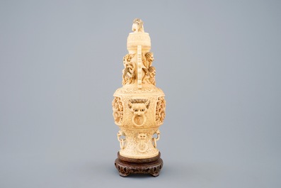 A Chinese carved ivory vase and cover on a wooden base, early 20th C.