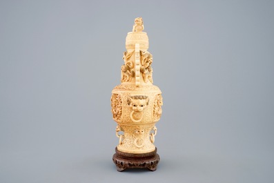 A Chinese carved ivory vase and cover on a wooden base, early 20th C.