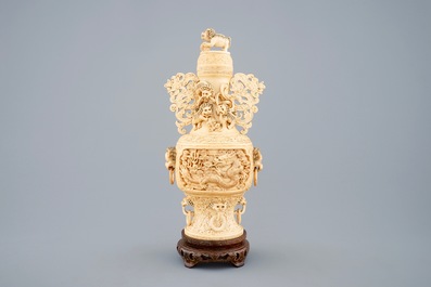 A Chinese carved ivory vase and cover on a wooden base, early 20th C.