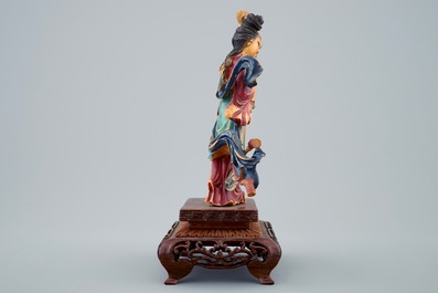 A Chinese polychrome carved ivory figure of a lady with flowers on wooden base, early 20th C.