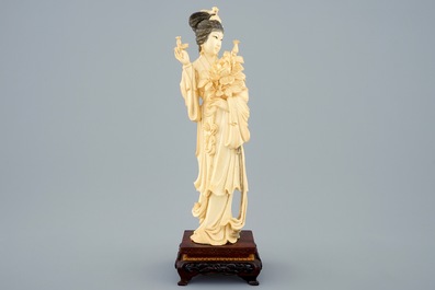 Une figure d'une femme aux fleurs en ivoire sculpt&eacute; sur socle, Chine, d&eacute;but du 20&egrave;me