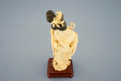 Een Chinese ivoren figuur van een vrouw met handtrommel op houten sokkel, begin 20e eeuw