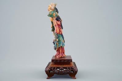 A Chinese polychrome carved ivory figure of a lady with flowers on wooden base, early 20th C.