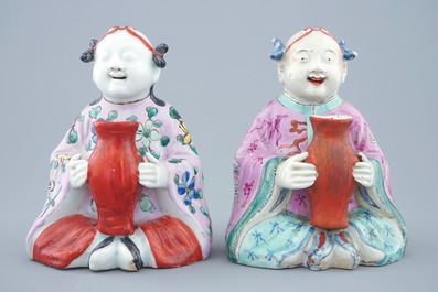 A pair of Chinese famille rose groups of seated boys holding a vase, 18/19th C.