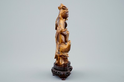 Une figure de Guanyin en pierre oeil de tigre sculpt&eacute;e sur socle en bois, 19/20&egrave;me