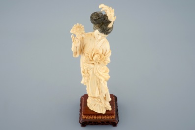 A Chinese carved ivory figure of a beauty with flowers on wooden base, early 20th C.