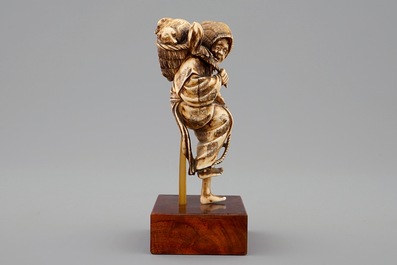 A Japanese ivory okimono of a lady with dogs, Meiji, 19th C.