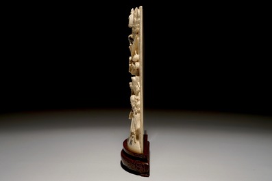 Een Chinese ivoren plaquette met onsterfelijken op houten sokkel, 2e kwart 20e eeuw