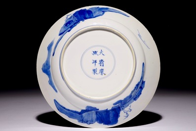 Une assiette en porcelaine de Chine bleu et blanc &agrave; d&eacute;cor de personnages dans un jardin, marque et p&eacute;riode de Kangxi