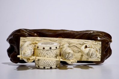 A large Japanese ivory okimono of boys playing a drum on a carved wooden base, Meiji, late 19th C., signed