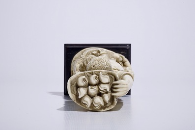 Un groupe en ivoire sculpt&eacute; d'un cueilleur de p&ecirc;ches sur socle en bois, Chine, d&eacute;but du 20&egrave;me