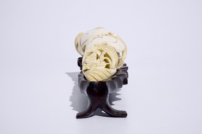 Un groupe en ivoire sculpt&eacute; en forme d'un coquillage sur socle en bois, d&eacute;but du 20&egrave;me