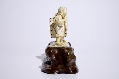 A large Japanese ivory okimono of boys playing a drum on a carved wooden base, Meiji, late 19th C., signed