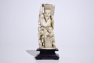 A Chinese ivory group of a peach picker on wooden base, early 20th C.