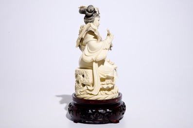 A Chinese ivory figure of a lady playing a flute on wooden base, early 20th C.