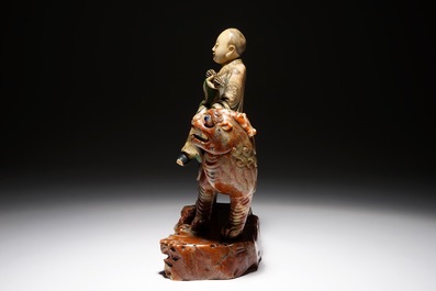 A Chinese soapstone figure of the immortal Vajraputra on a Buddhist lion, Kangxi/Qianlong