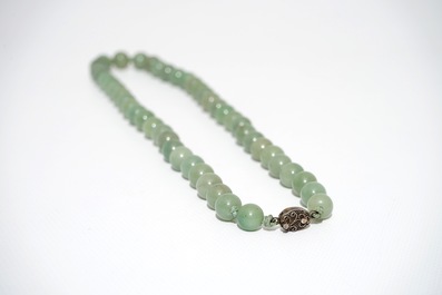 A Chinese green jade beads necklace with silver lock, 19/20th C.