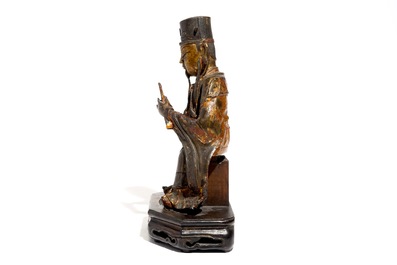 A Chinese partly gilt and polychrome bronze figure of Wenchang Dijun on wooden stand, Ming