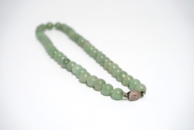 A Chinese green jade beads necklace with silver lock, 19/20th C.