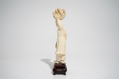 A Chinese carved ivory figure of a lady with a fruit basket, 2nd quarter 20th C.