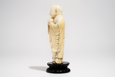 Een Chinese ivoren figuur van Boeddha met waaier, op lotusvormige sokkel, 19e eeuw