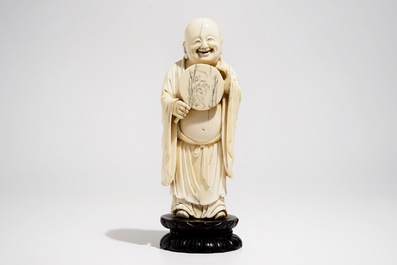 A Chinese carved ivory figure of Buddha holding a fan, on lotus-shaped base, 19th C.