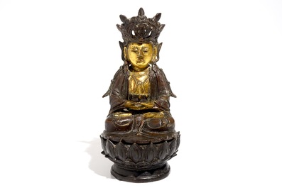 A partly gilt Chinese bronze figure of Buddha seated on a lotus throne, late Ming