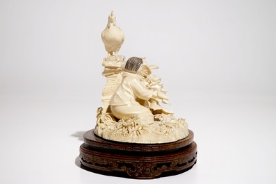 A Chinese ivory group with a girl on a wooden stand, 2nd quarter 20th C.