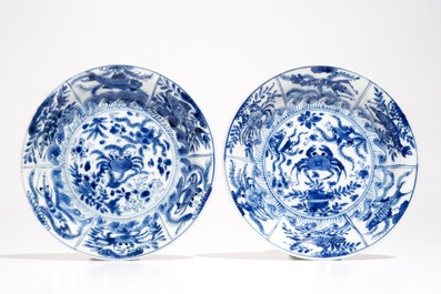 A pair of Chinese bleu and white cups and saucers with crabs and fish, Kangxi