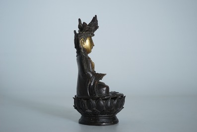 A partly gilt Chinese bronze figure of Buddha seated on a lotus throne, late Ming