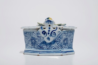 A Dutch Delft blue and white butter tub with polychrome finial, 18th C.